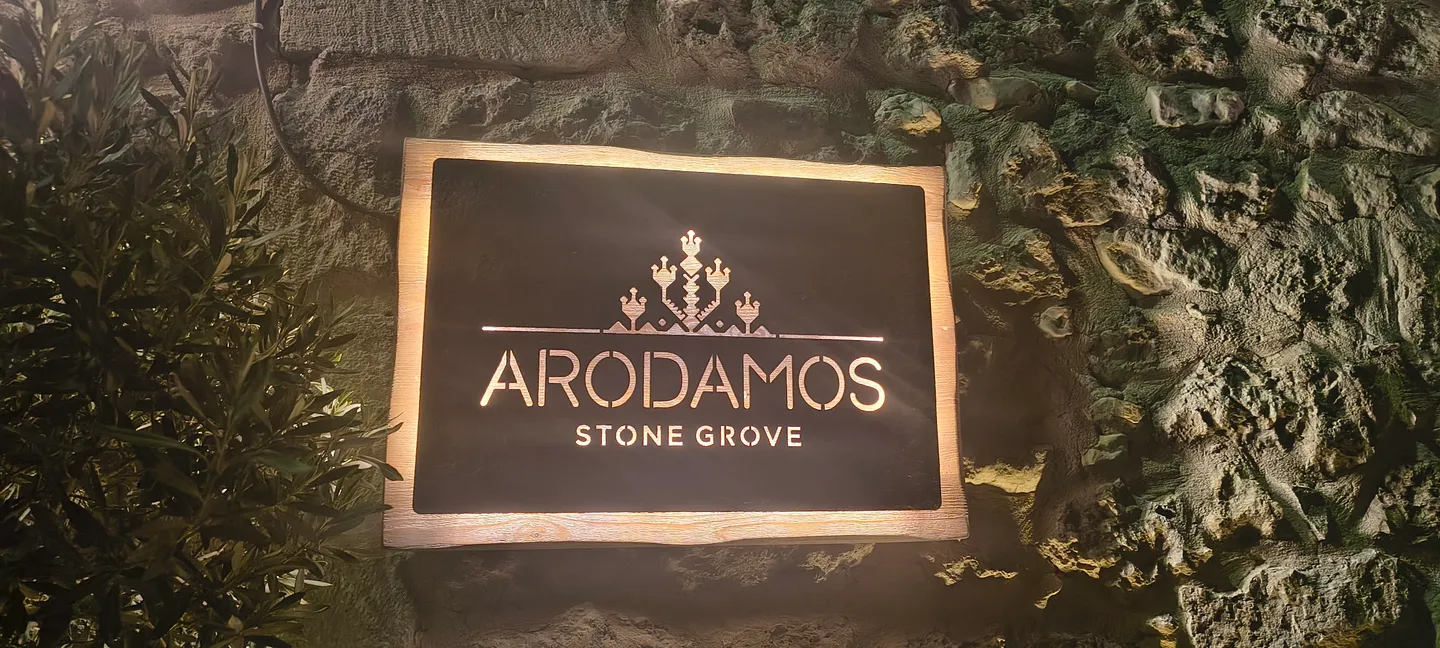 Schild mit dem Schriftzug Arodamos Stone Grove an einer Natursteinmauer