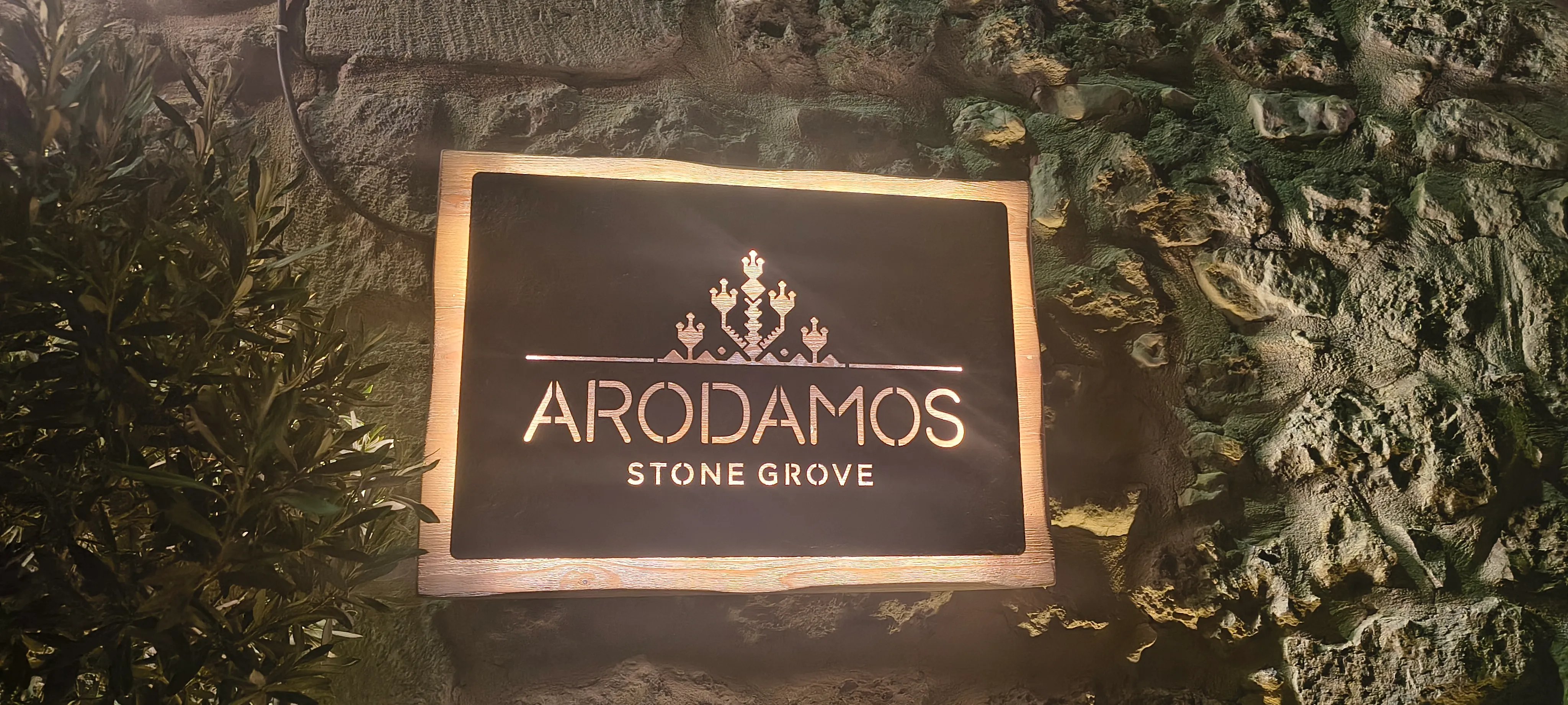 Schild mit dem Schriftzug Arodamos Stone Grove an einer Natursteinmauer