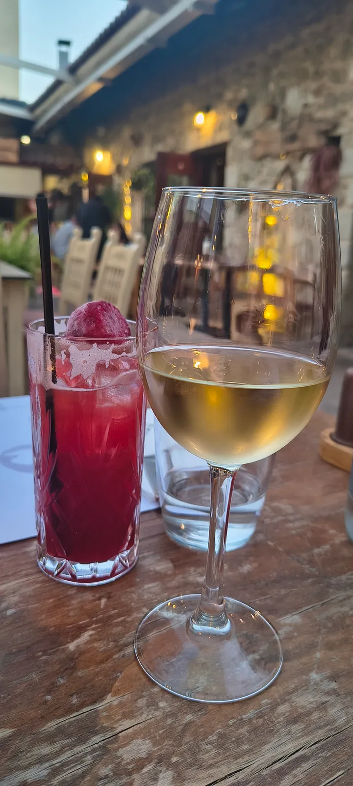 Weißwein und ein roter Cocktail auf einem Holztisch im Arodamos Stone Grove